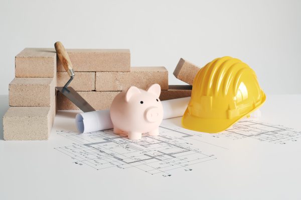 Bricks, work tools, piggy bank and house plan: building and construction project