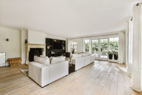 Contemporary minimalist style interior design of light studio apartment with wooden table and chairs in dining zone between open kitchen and living room with white walls and parquet floor